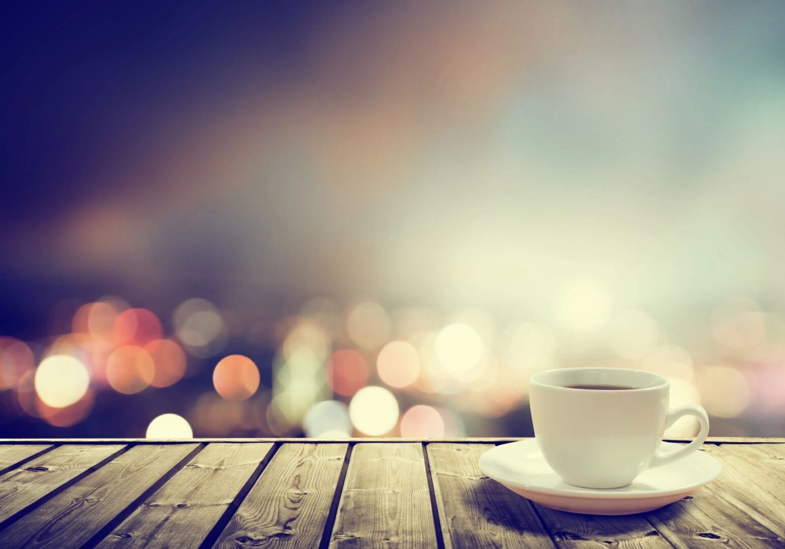 Coffee cup on wooden table with bokeh lights